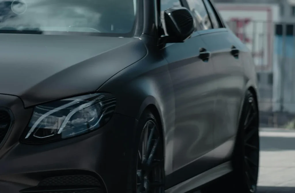 Side profile of a dark matte luxury car highlighting professional car detailing and paint care.